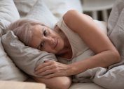 Một người phụ nữ lớn tuổi nằm thao thức trên giường với khuôn mặt lo lắng