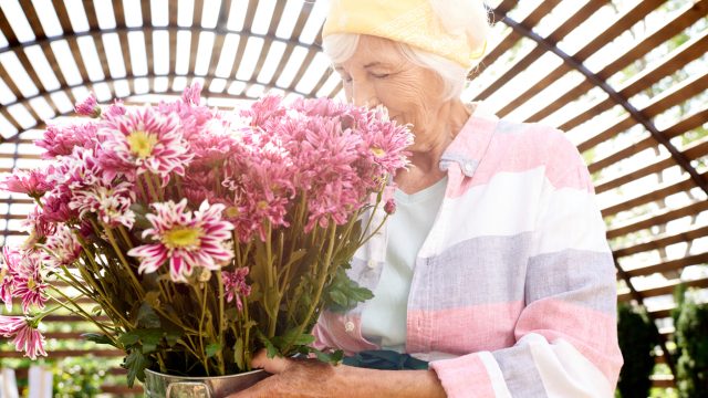 A senior woman smelling a bunch of flowers