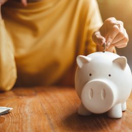 Woman putting money in piggy bank for retirement