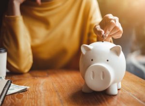 Woman putting money in piggy bank for retirement