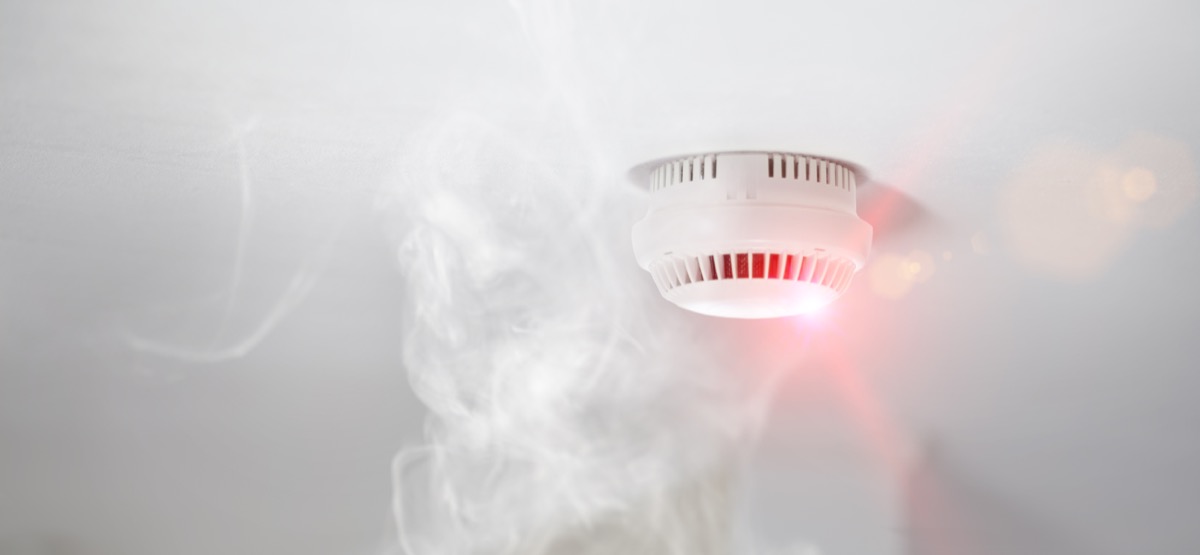 ceiling mounted smoke detector surrounded by smoke