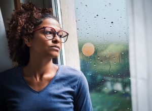 Woman looking out window during a storm