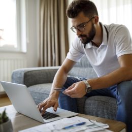 Young man shopping online with credit card at home
