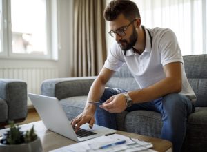Young man shopping online with credit card at home