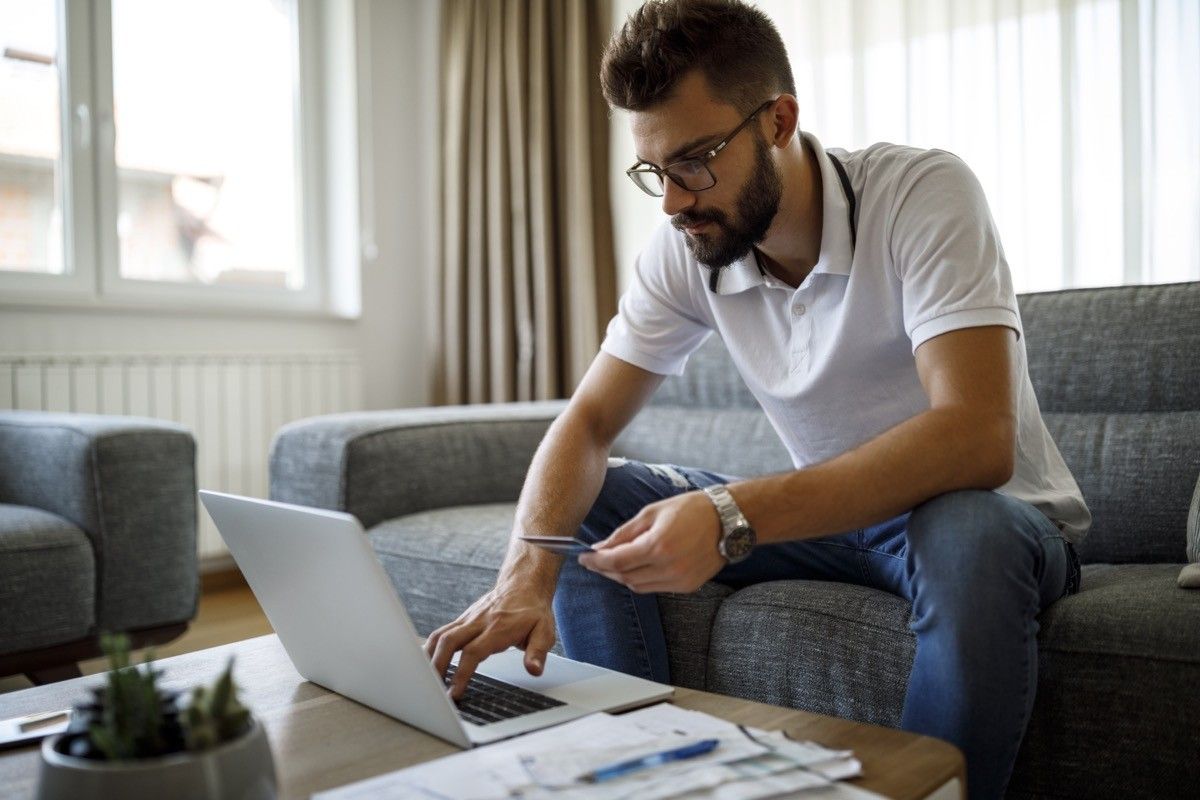 Young man shopping online with credit card at home