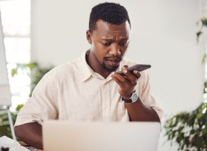 Shot of a young businessman talking on a cellphone while using a laptop in an office