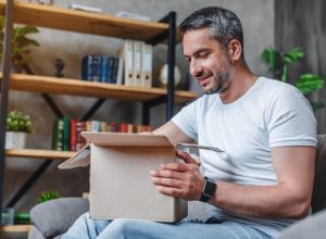 Happy middle aged man with cardboard boxes delivery at home