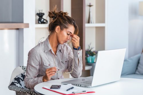 Femeie cu dureri de cap tensionate stând la birou
