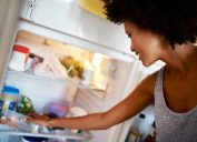 A young woman reaching into the fridge for food
