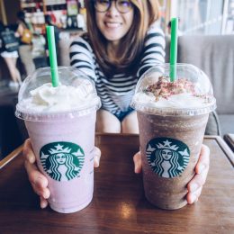 A woman handing over two Starbucks coffee drinks