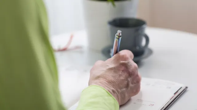 Older person writing on paper