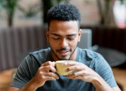 A young man drinking a cup of coffee in a cafe