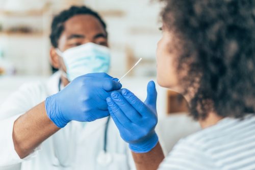 Ein Arzt mit Schutzhandschuhen testet bei einem jungen Patienten einen Nasenabstrich auf Coronavirus