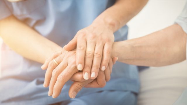 Doctor or nurse holding hands with patient