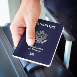 Close-up of someone holding an American passport over their suitcase
