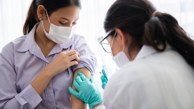 A young woman receiving a COVID-19 vaccine from a healthcare worker