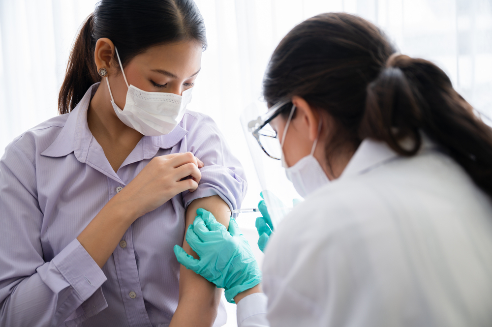 A young woman receiving a COVID-19 vaccine from a healthcare worker