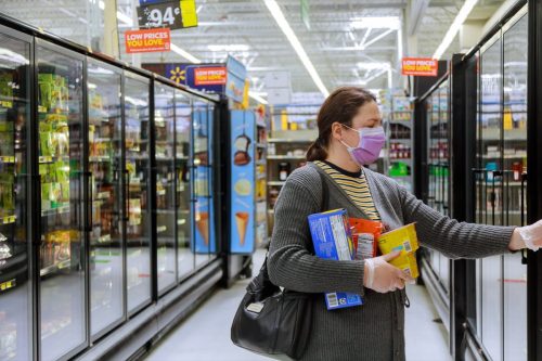 Walmart supermarket Los Angeles CA US 16 MAY 2020: Shopping on supermarket during the Coronavirus COVID-19 pandemic on customer in a supermarket choosing, with woman wearing disposable medical mask