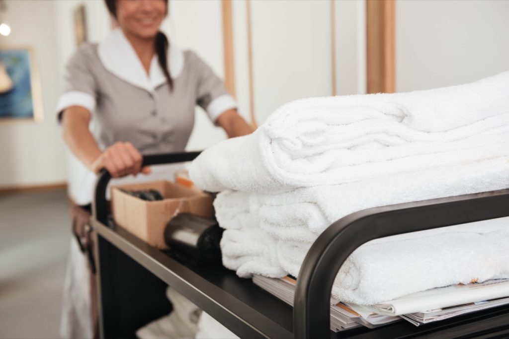 Hình ảnh cắt xén của người giúp việc khách sạn trẻ mang theo khăn sạch và các vật dụng khác