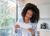 woman reading the mail at home and smiling - lifestyle concepts