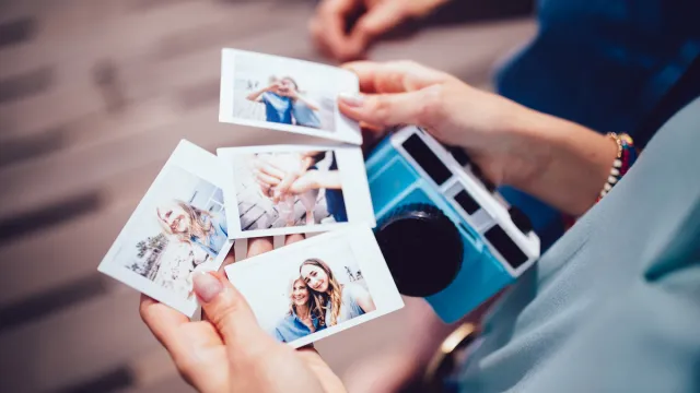 Close up of woman's hands holding instant photos taken on polaroid camera on summer vacations