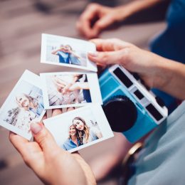 Close up of woman's hands holding instant photos taken on polaroid camera on summer vacations