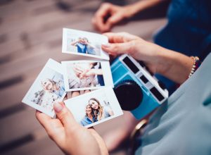 Close up of woman's hands holding instant photos taken on polaroid camera on summer vacations
