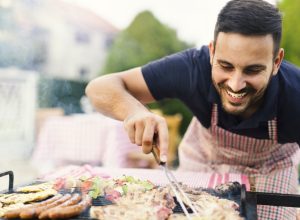 30-something man checking meat on the grill
