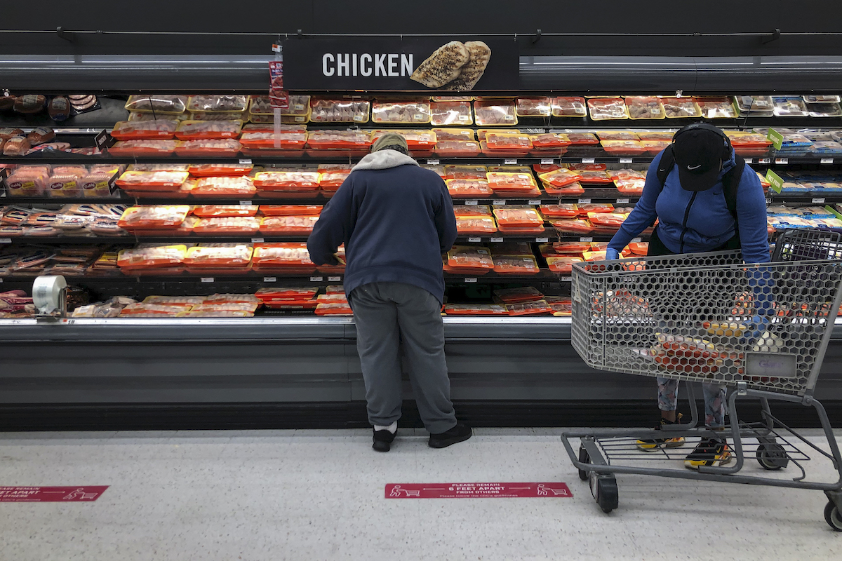 Shoppers browse in the chicken section at a grocery store