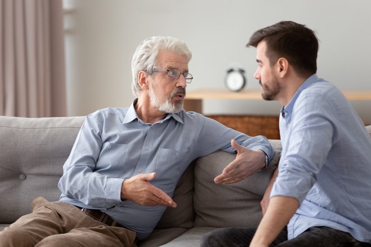 Gefährlicher 60er-Vater und erwachsener Sohn sitzen auf dem Sofa und führen wichtige Gespräche, die versuchen, die Probleme des Lebens zu lösen Konzept der Kommunikation zwischen verschiedenen Männern im Haus