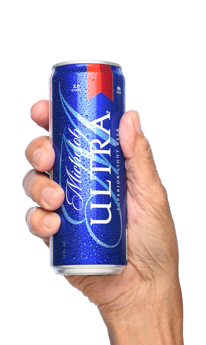Closeup of a hand holding a can of Michelob Ultra Beer. A a low carb and low calorie light beer from Anheuser-Busch.