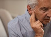A senior man holding his ear suffering from hearing impairment or loss