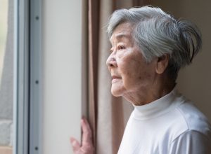 A senior woman looking out the window of her home