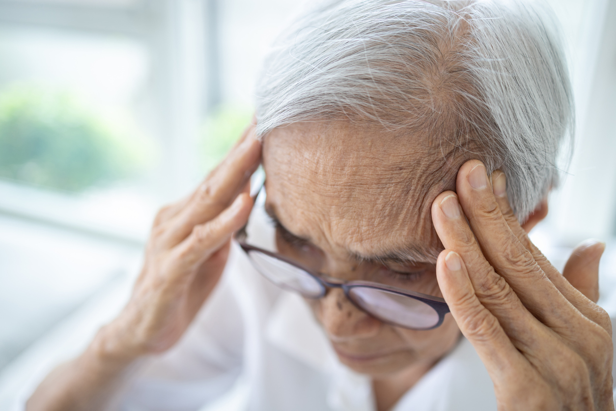 O femeie în vârstă se freacă pe cap și prezintă semne ale unui posibil accident vascular cerebral