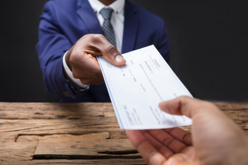 Man in suit handing a paycheck to someone