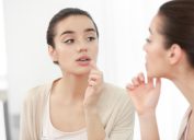 woman looking at her mouth in mirror