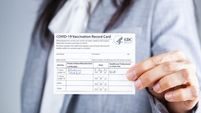 Woman is showing her CDC issued COVID vaccination record card as a proof of immunization.