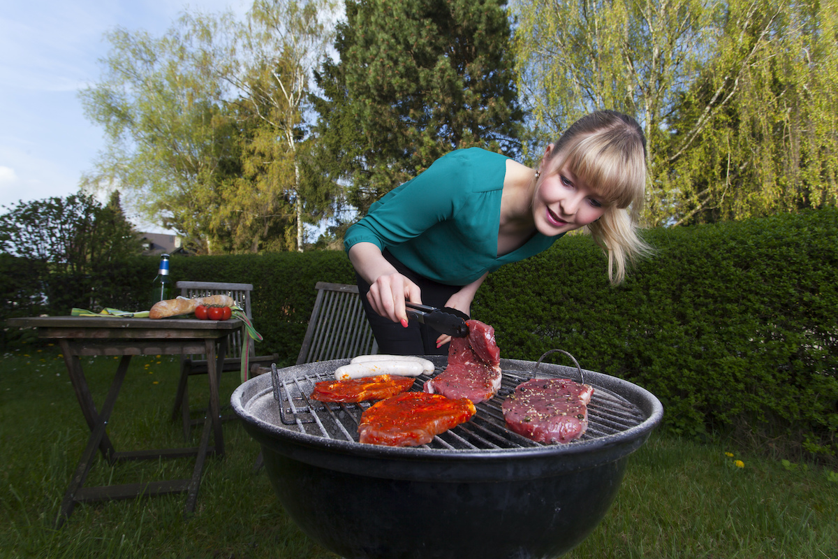 Woman cooking steak on barbecue