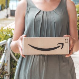 woman wearing gray dress and holding amazon box