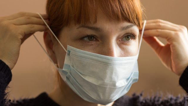 Closeup of a young woman putting on a protective face mask