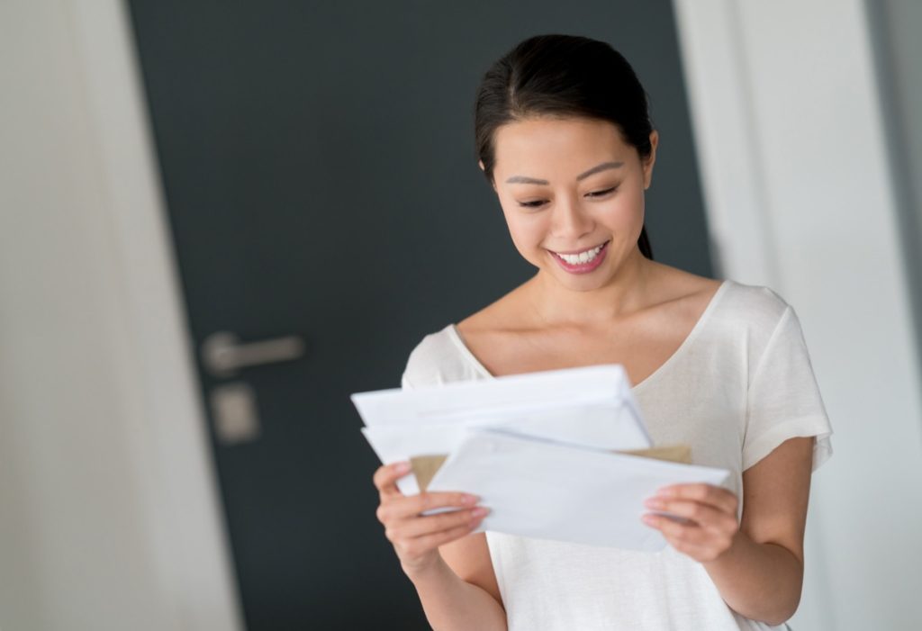 woman at home checking her mail and looking very happy