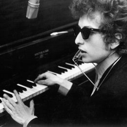 Bob Dylan 1965 at a piano with sunglasses