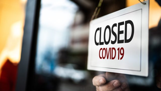 A "closed due to COVID-19" sign being put up on a door