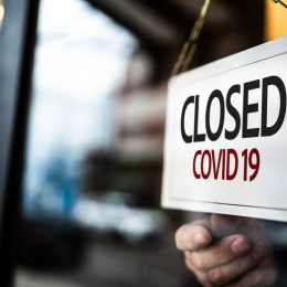 A "closed due to COVID-19" sign being put up on a door