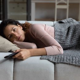 Tired millennial female relax at home after hard work day switch on favorite series