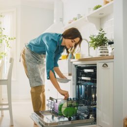 Woman loading a dishwasher without pre-rinsing dishes before