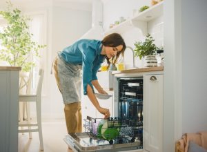 Woman loading a dishwasher without pre-rinsing dishes before