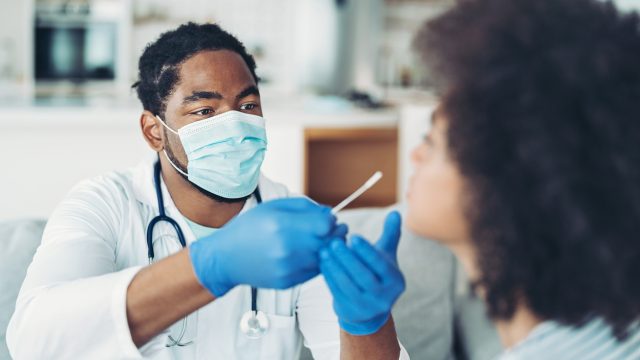 A doctor administering a nasal swab for a COVID test on a young woman