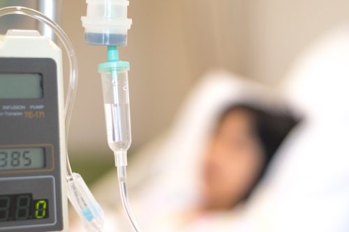 Ein Kinderpatient mit einem Infusionsschlauch in der Hand schläft auf einem Krankenhausbett.  Gesundheitskonzept der medizinischen Analgesie