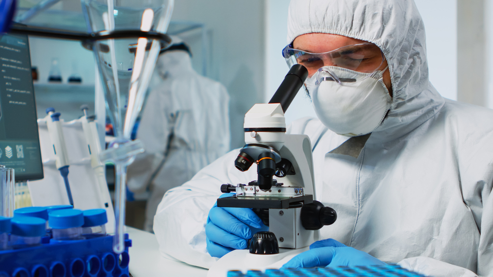 A lab technician looks at samples through a microscope